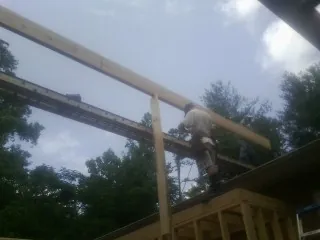 Carpenter setting a ridge beam over a new addition frame — Ice Dam Removal by Roofing Brothers in Haralson