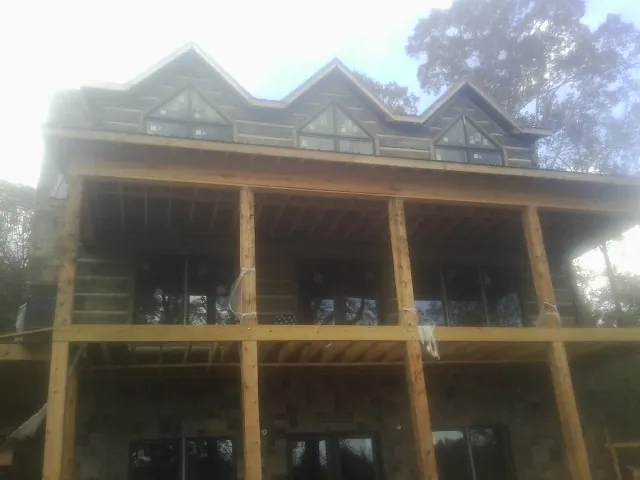 Dormers and porch framing on a large log home under construction — Roof Coating work by our crew in Haralson