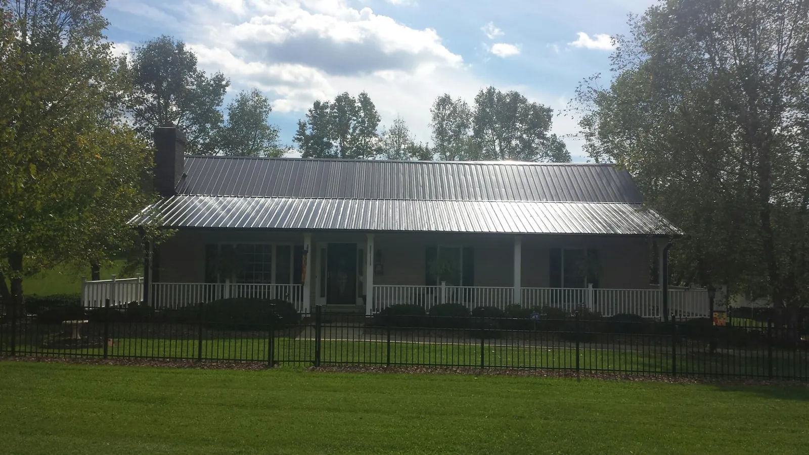 Gray metal roof on a brick ranch with a full width front porch — Gutter Guard Installation work by our crew in Haralson