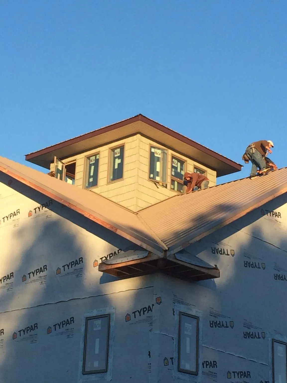 Roofers working around a rooftop cupola on a new metal roof at sunset — Roof Waterproofing in Haralson by Roofing Brothers